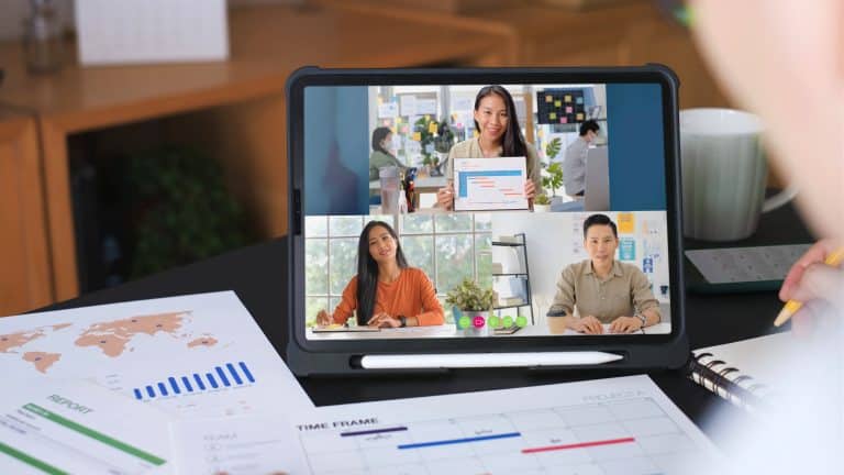 A tablet screen showing a virtual webinar with three professionals discussing project timelines, representing the best webinar software 2025 for online meetings.
