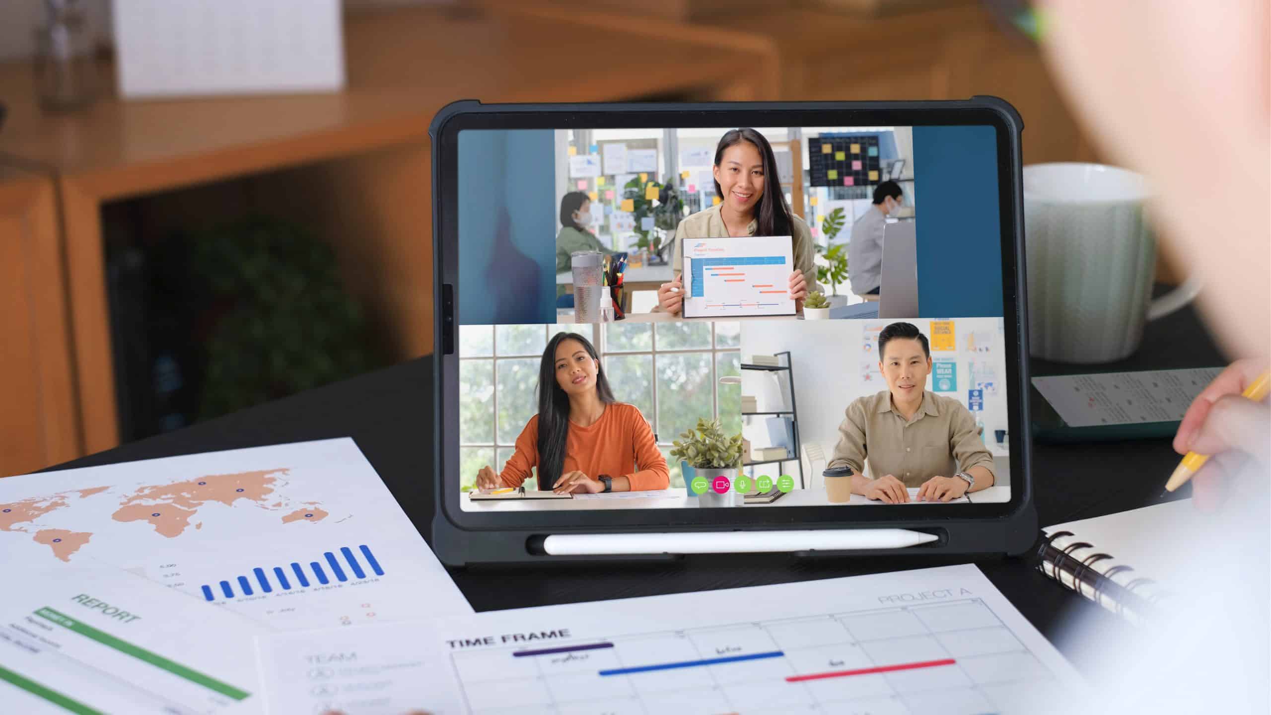 A tablet screen showing a virtual webinar with three professionals discussing project timelines, representing the best webinar software 2025 for online meetings.